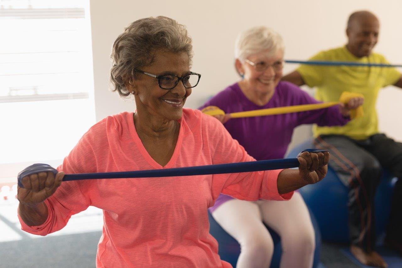 A group of over-65s doing seated strength exercises with stretchy bands